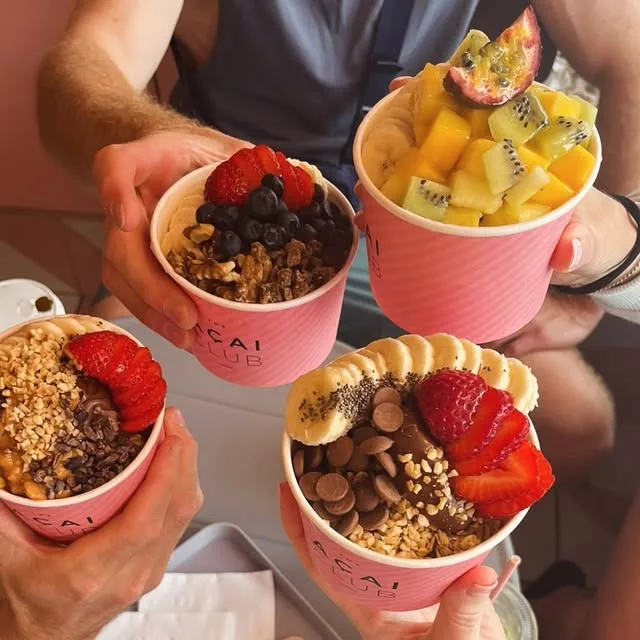 Friends cheersing with açai bowls